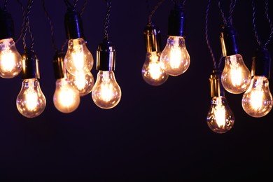 Photo of Glowing light bulbs hanging on color background