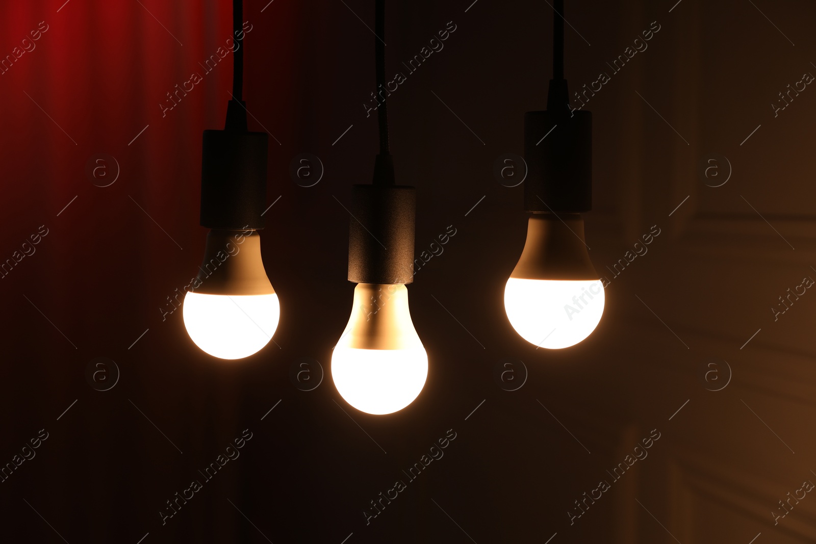 Photo of Glowing light bulbs hanging indoors, closeup view