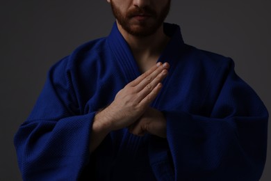 Photo of Karate fighter in uniform on grey background, closeup