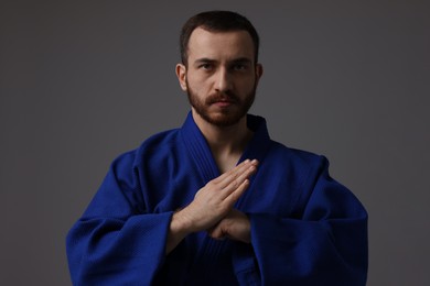 Photo of Karate fighter in uniform on grey background