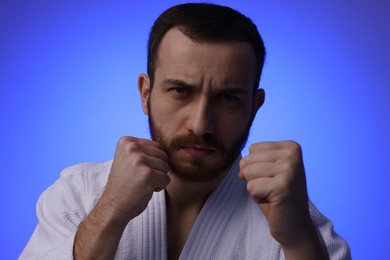 Photo of Karate fighter in uniform on blue background