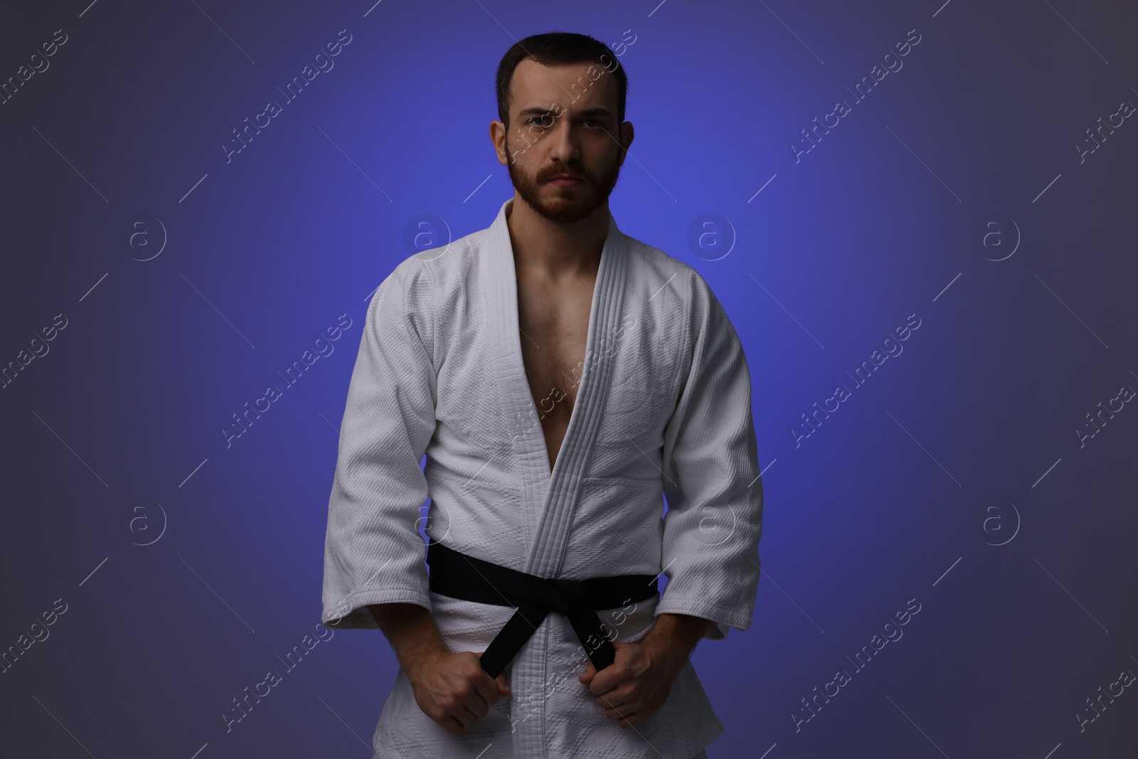 Photo of Karate fighter in uniform on dark purple background