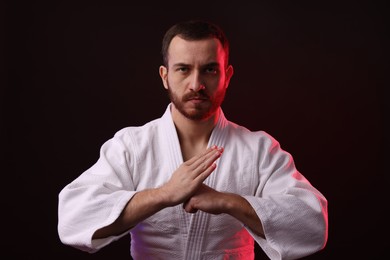 Photo of Karate fighter wearing uniform in color light against black background