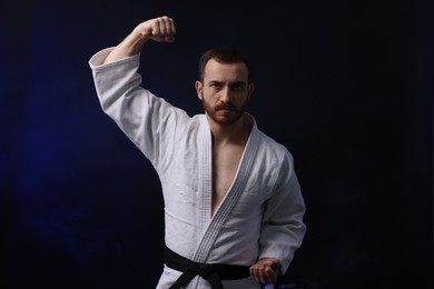 Photo of Man in uniform practicing karate on dark background