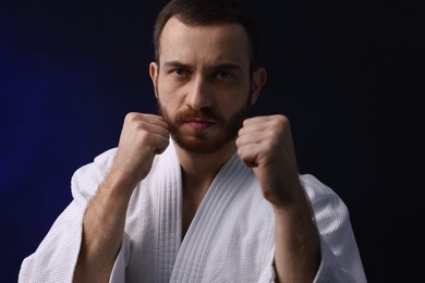 Photo of Karate fighter in uniform on dark background