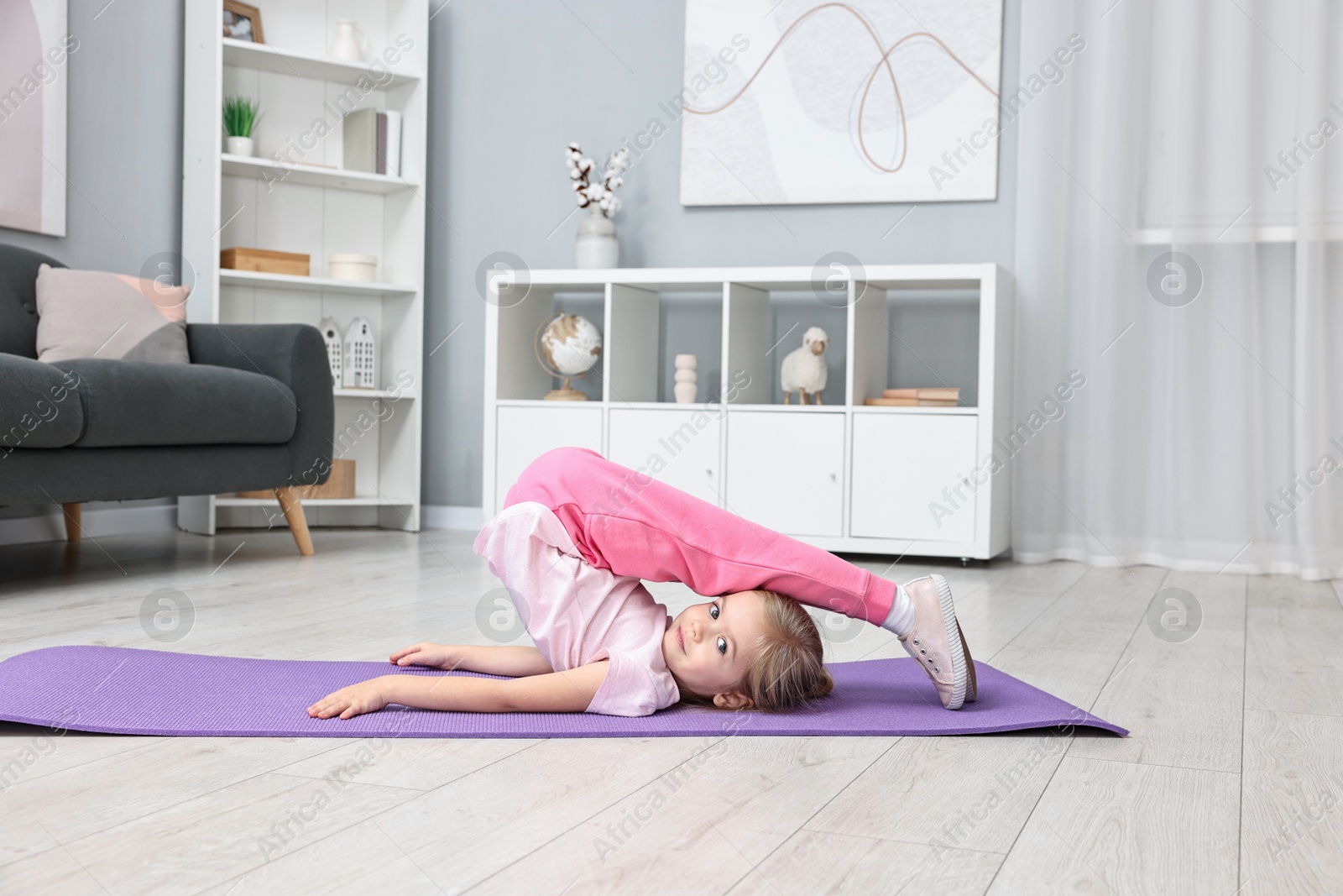 Photo of Little girl exercising on fitness mat at home. Sport activity