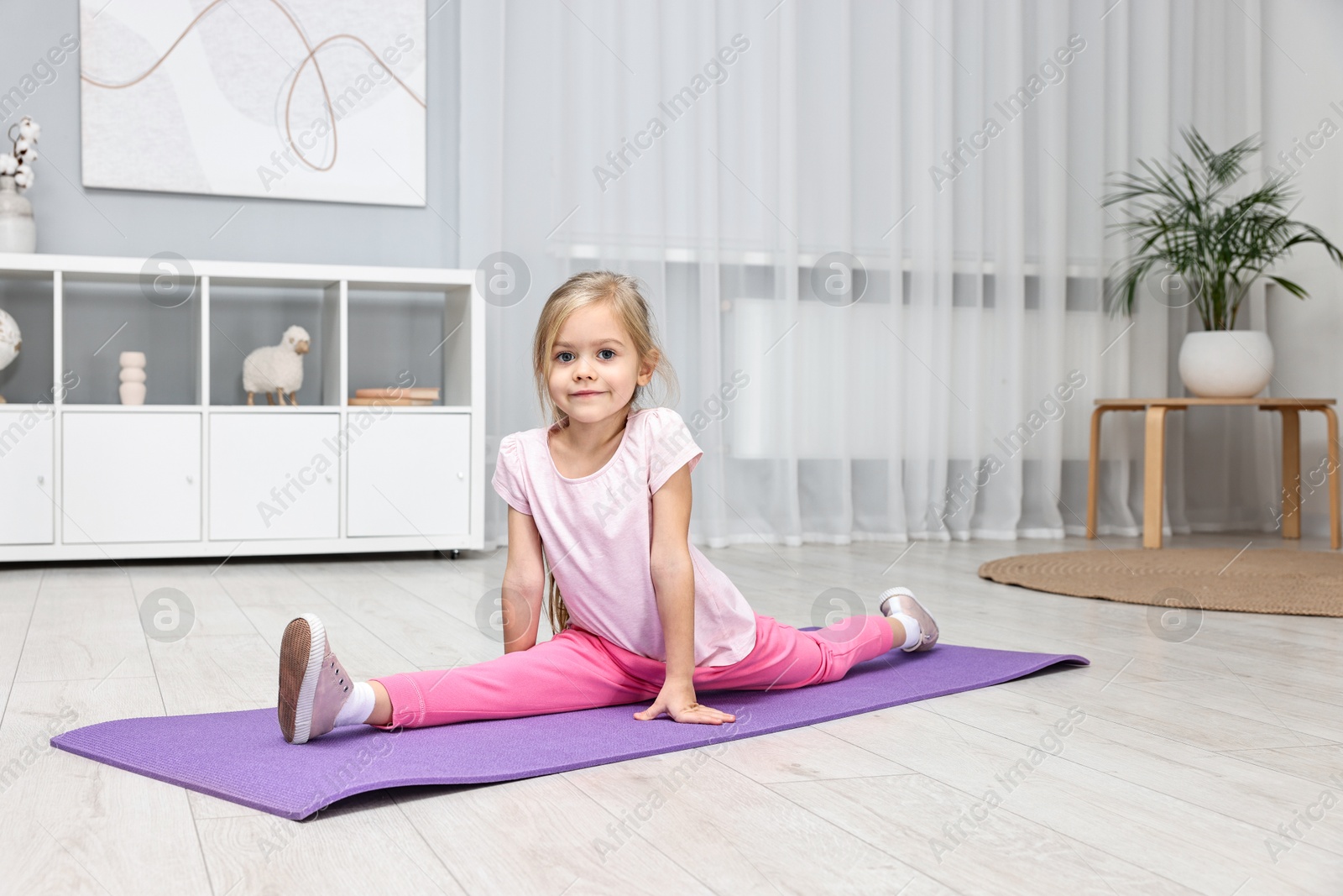 Photo of Little girl exercising on fitness mat at home. Sport activity