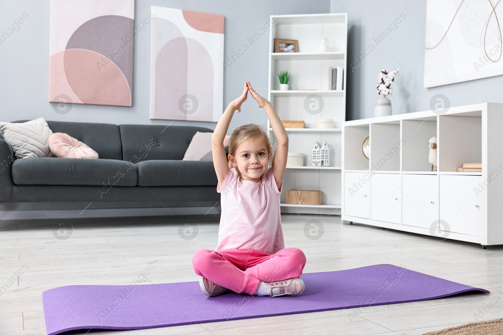 Photo of Little girl exercising on fitness mat at home. Sport activity