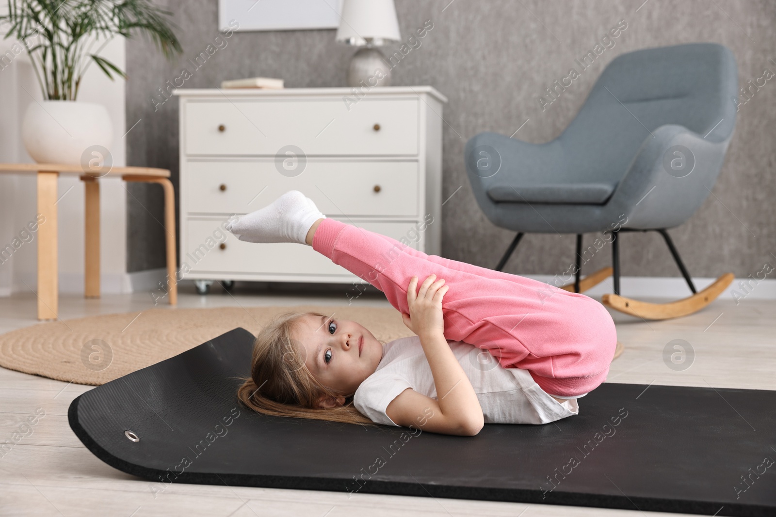 Photo of Little girl exercising on fitness mat at home. Sport activity