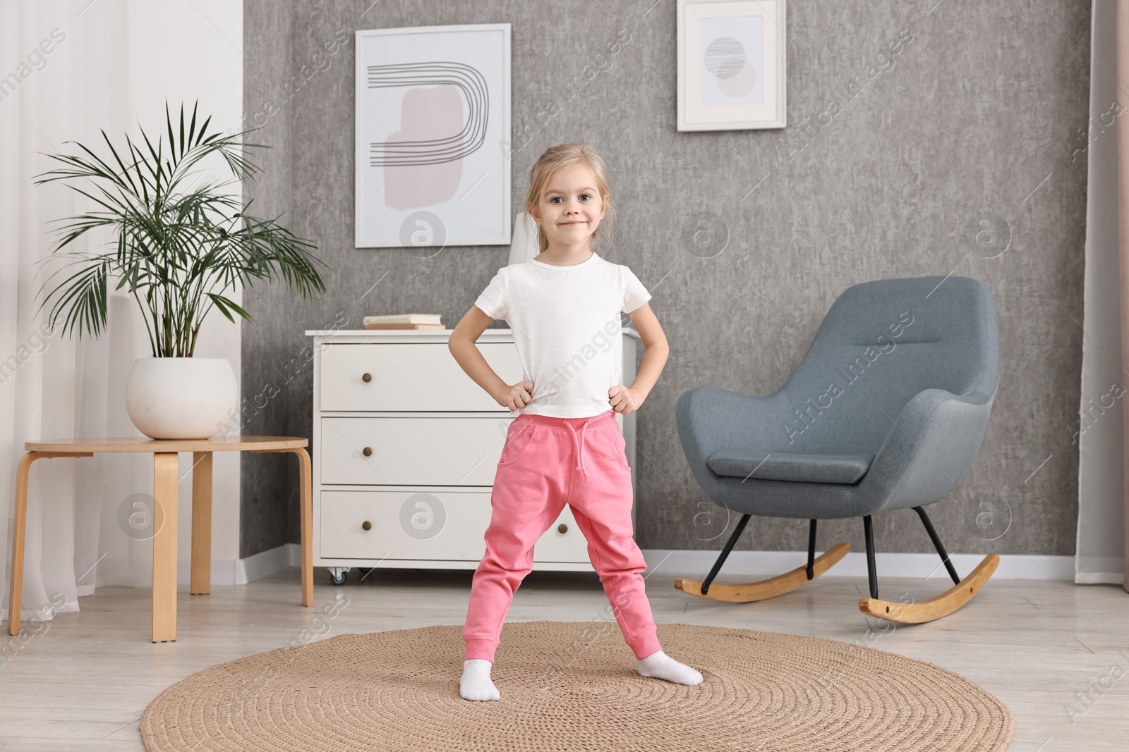 Photo of Little girl exercising on rug at home. Sport activity