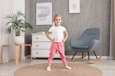 Photo of Little girl exercising on rug at home. Sport activity