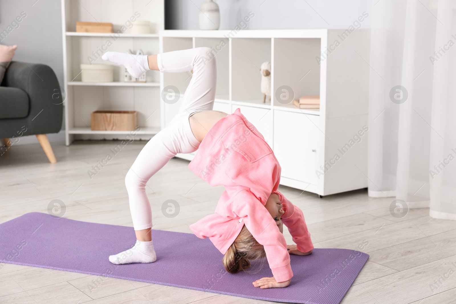 Photo of Little girl exercising on fitness mat at home. Sport activity