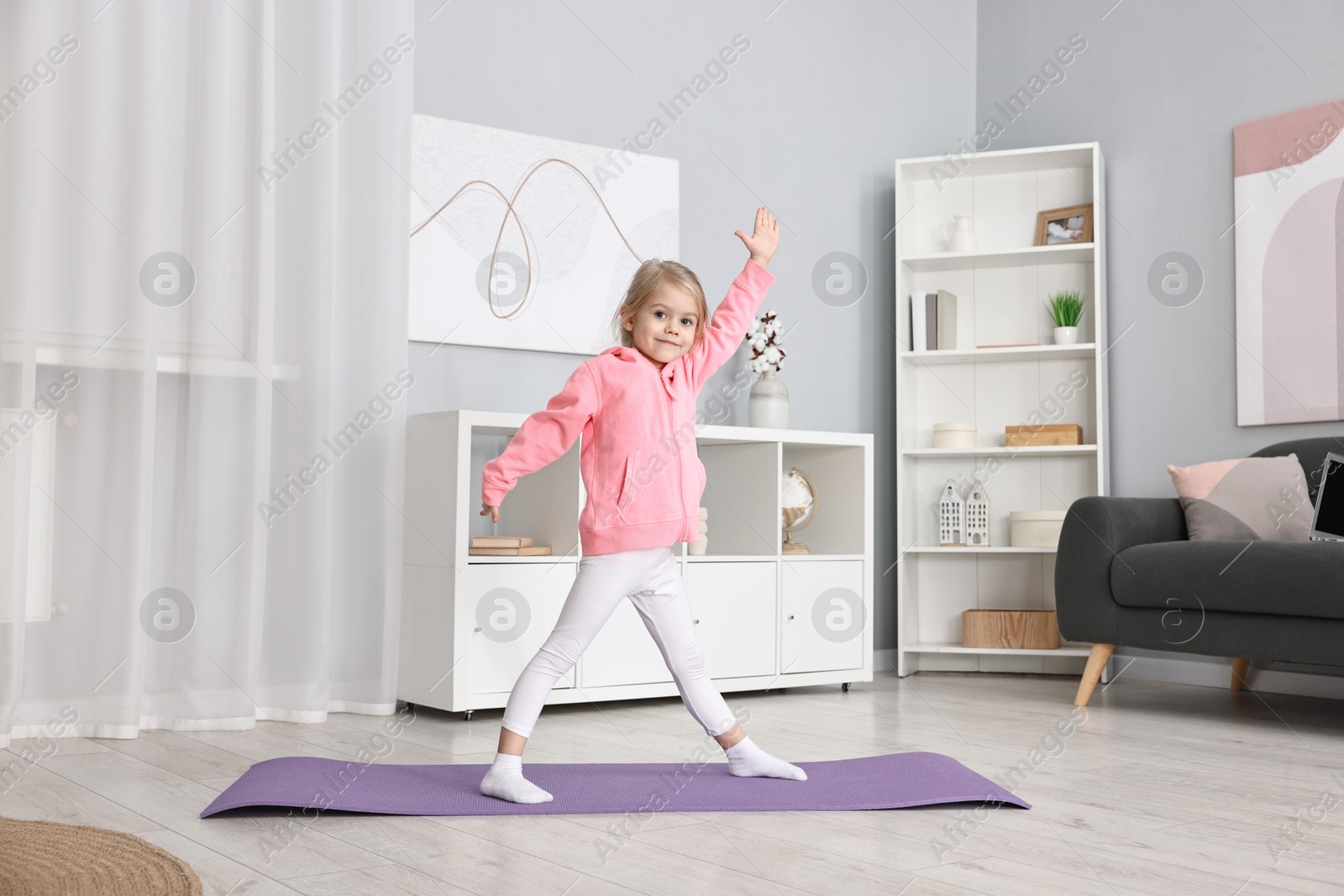 Photo of Little girl exercising on fitness mat at home. Sport activity