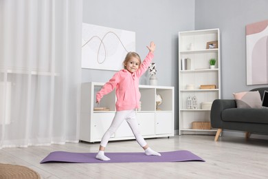 Photo of Little girl exercising on fitness mat at home. Sport activity