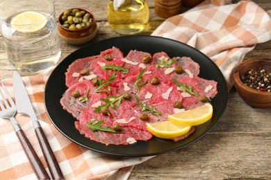 Photo of Delicious beef carpaccio served on wooden table, closeup