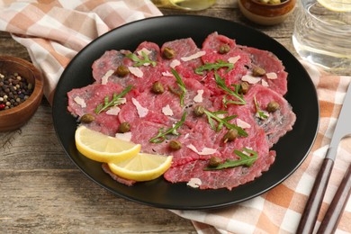 Delicious beef carpaccio served on wooden table, closeup