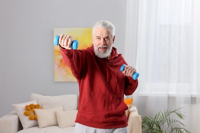 Photo of Elderly man exercising with dumbbells at home