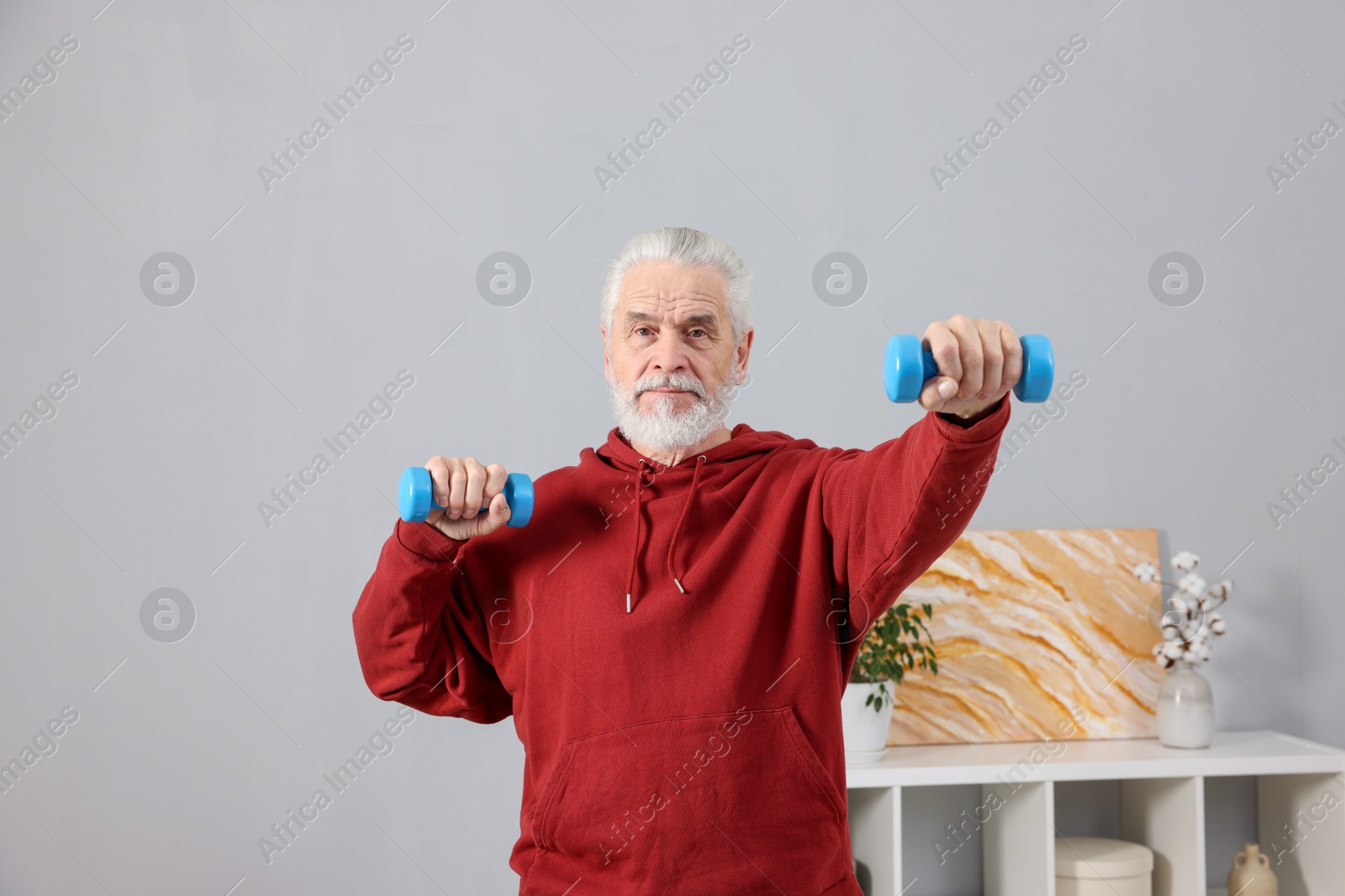 Photo of Elderly man exercising with dumbbells at home