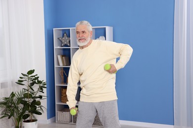 Photo of Elderly man exercising with dumbbells at home