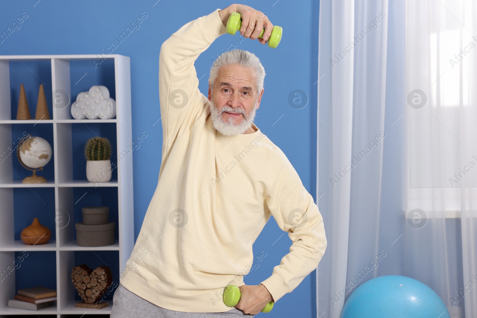 Photo of Elderly man exercising with dumbbells at home