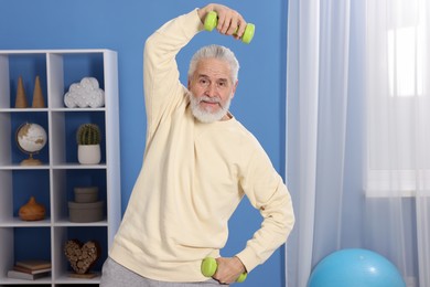 Photo of Elderly man exercising with dumbbells at home