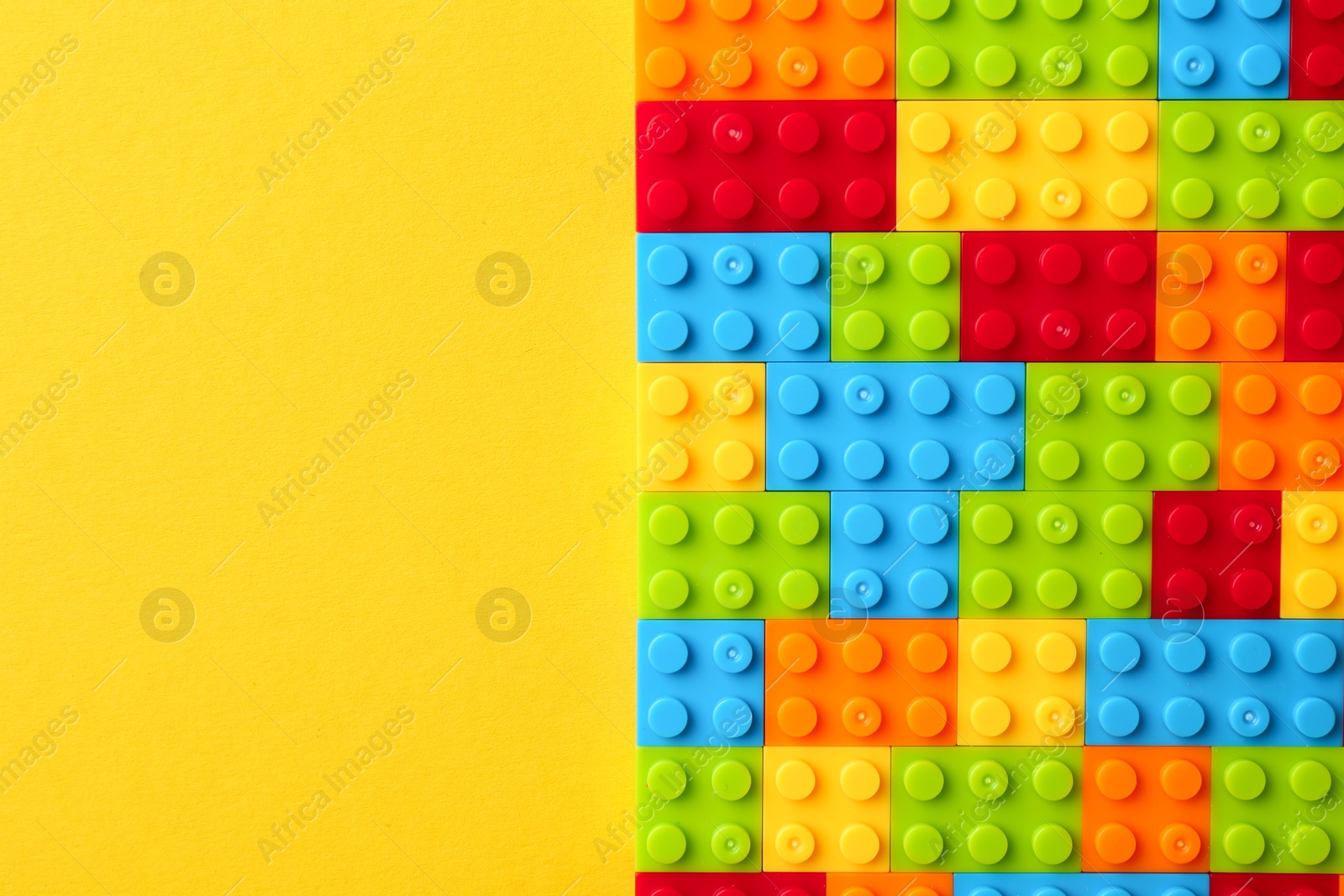 Photo of Constructor toy. Many colorful building blocks on yellow background, top view. Space for text