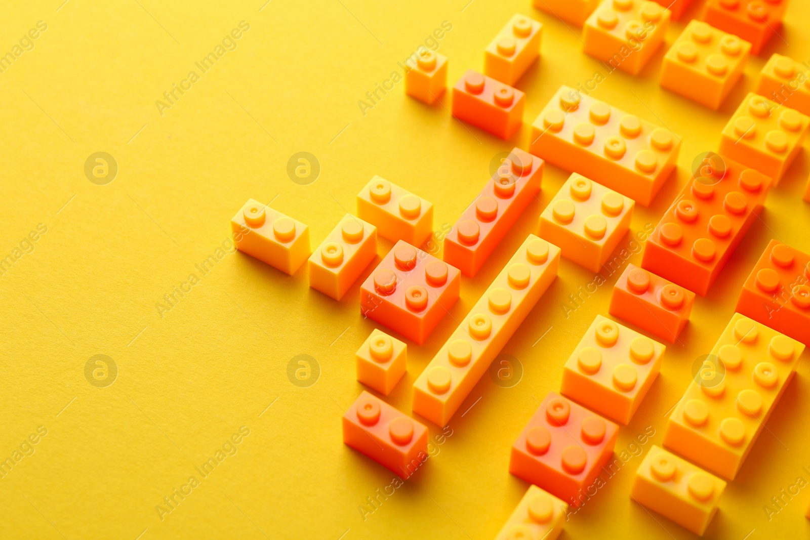 Photo of Constructor toy. Many building blocks on yellow background, above view. Space for text