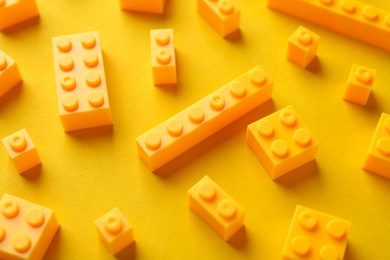 Photo of Constructor toy. Many building blocks on yellow background, closeup