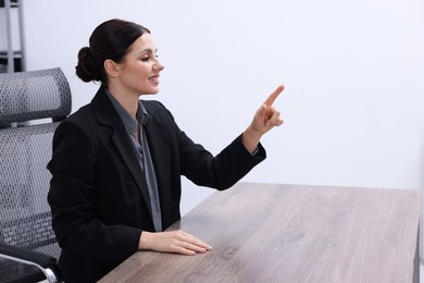 Photo of Beautiful woman pointing at something in office, space for text