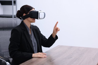 Photo of Woman using virtual reality headset in office, space for text