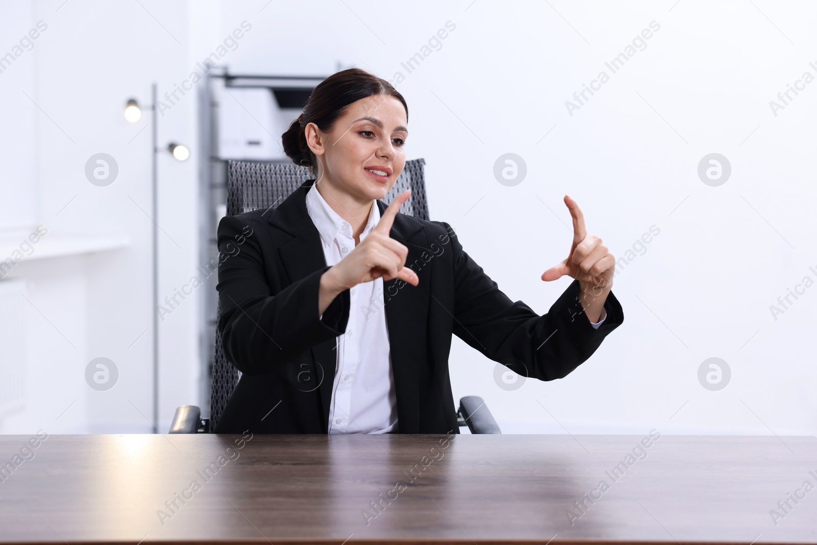 Photo of Beautiful woman showing something at wooden table in office