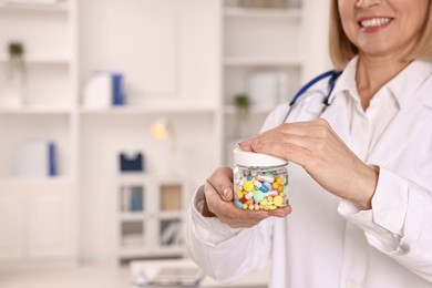 Photo of Happy nutritionist with container of weight loss pills in clinic, closeup. Space for text