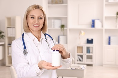 Photo of Happy nutritionist with bottle of weight loss pills in clinic. Space for text