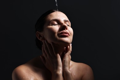 Photo of Attractive woman washing her face on black background