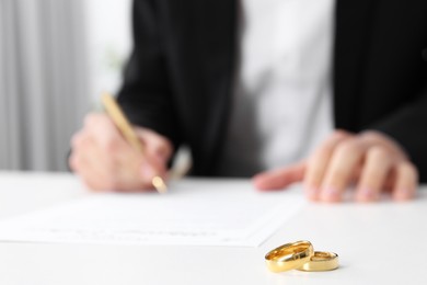 Photo of Man signing marriage contract and wedding rings on desk, selective focus