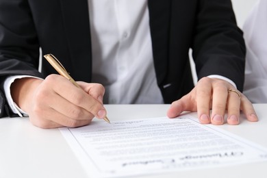 Photo of Man signing marriage contract at desk, closeup