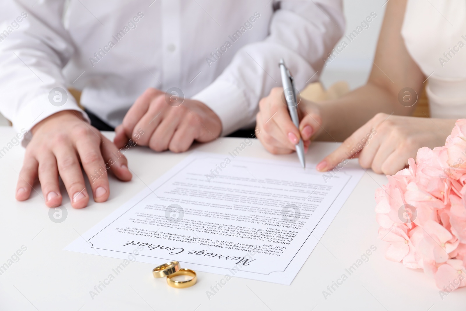 Photo of Newlyweds signing marriage contract and wedding rings on desk, selective focus