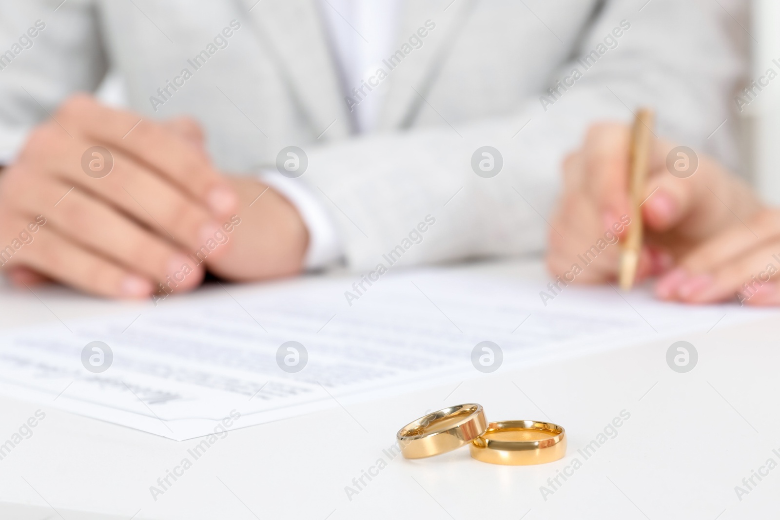 Photo of Newlyweds signing marriage contract and wedding rings on desk, selective focus