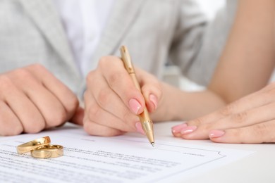 Photo of Newlyweds signing marriage contract and wedding rings on desk, selective focus