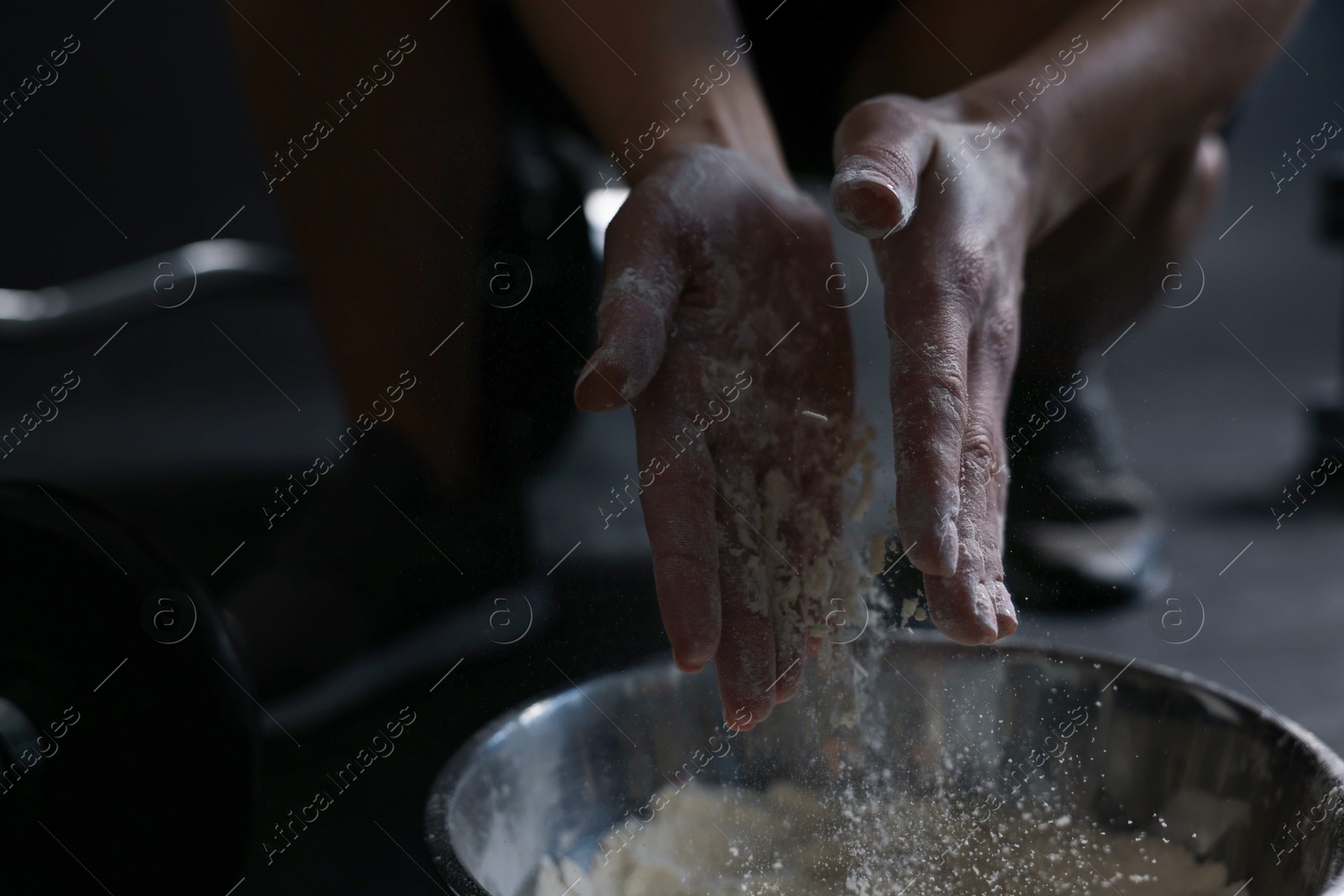 Photo of Woman applying talcum powder onto her hands above bowl before training in gym, closeup