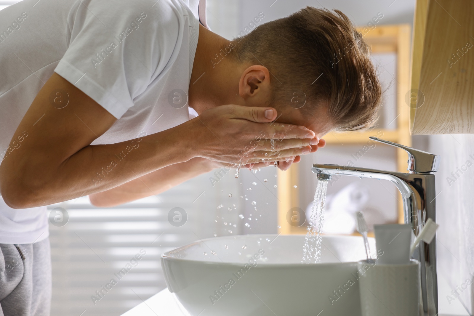 Photo of Man washing his face over sink in bathroom