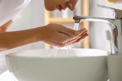 Photo of Man washing his face over sink in bathroom, closeup