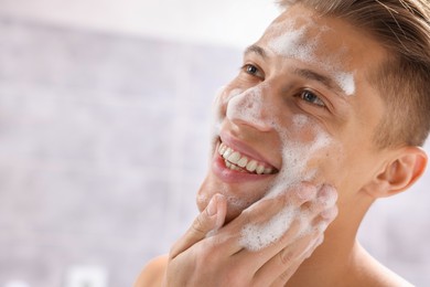 Photo of Man washing his face with cosmetic product in bathroom, closeup. Space for text