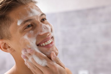 Photo of Man washing his face with cosmetic product in bathroom, closeup. Space for text