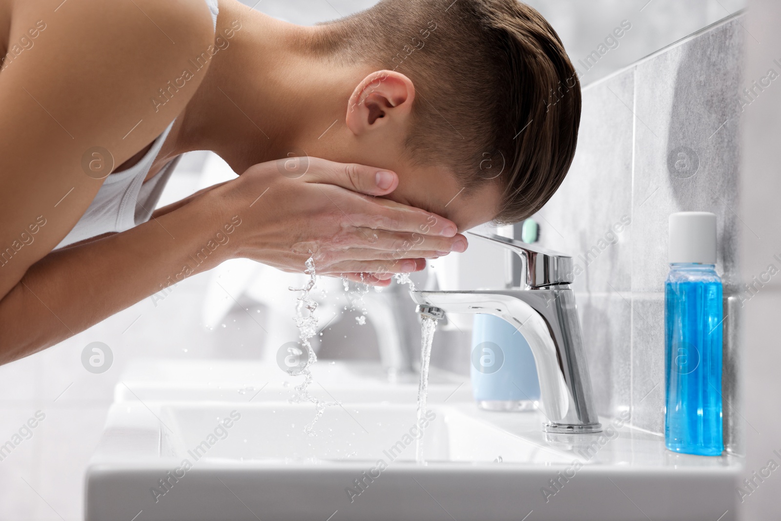 Photo of Man washing his face over sink in bathroom