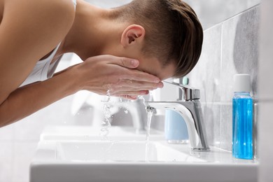 Photo of Man washing his face over sink in bathroom