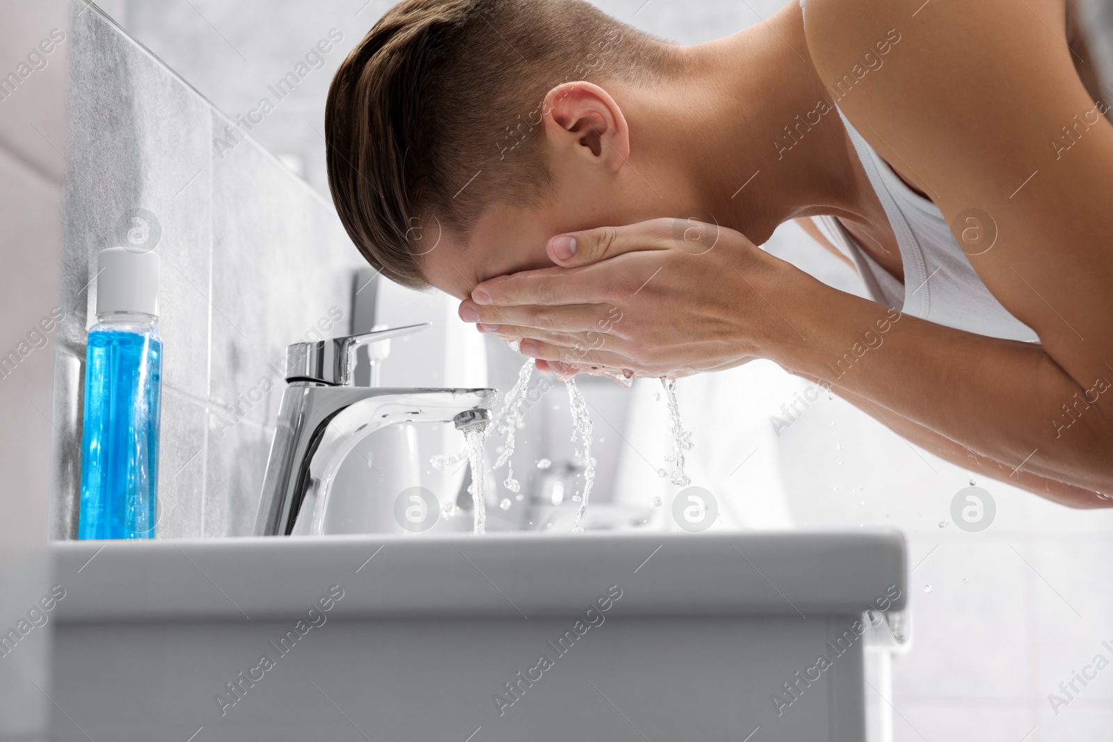 Photo of Man washing his face over sink in bathroom