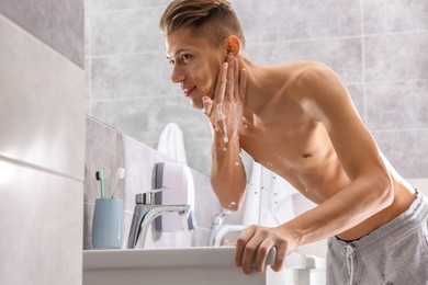 Photo of Man washing his face over sink in bathroom