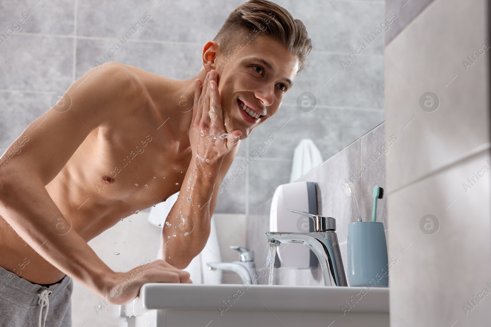 Photo of Man washing his face over sink in bathroom