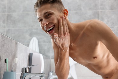 Photo of Happy man washing his face in bathroom